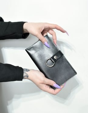 tattooed hands holding leather wallet with o-ring