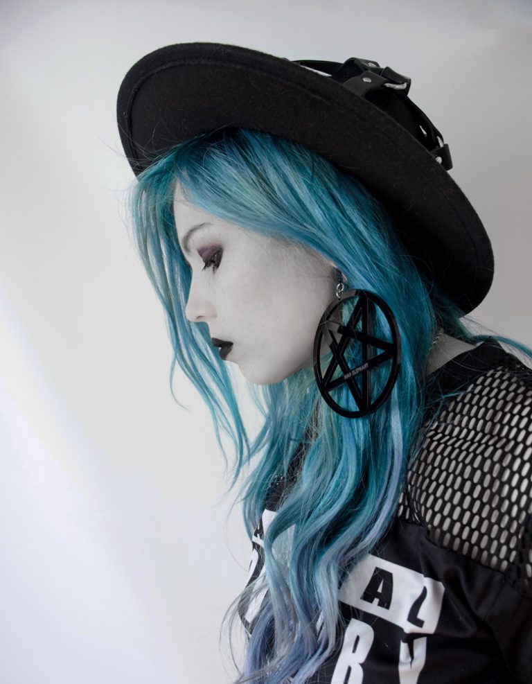pretty goth girl wearing pentagram earrings and hat