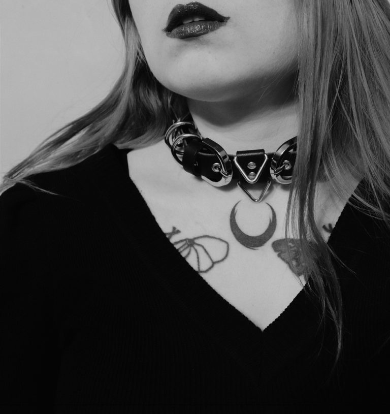 Tattooed goth girl wearing leather neck collar with rings