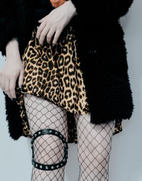 goth girl in fishnet wearing leg harness with spikes